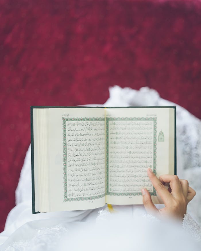 A person reading the Quran, focusing on the text with hands gently touching the page.